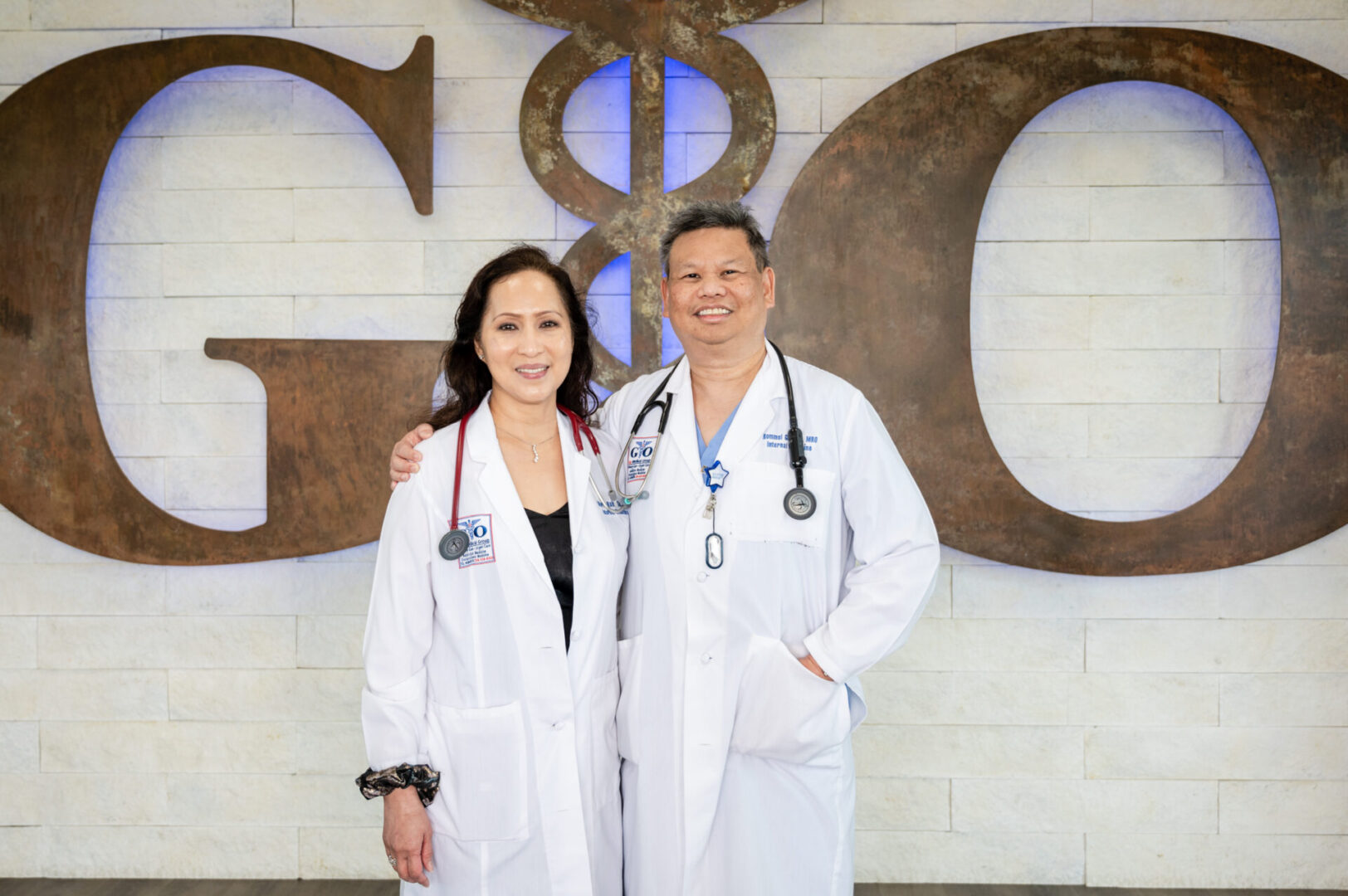 Two doctors standing in front of a large sign.