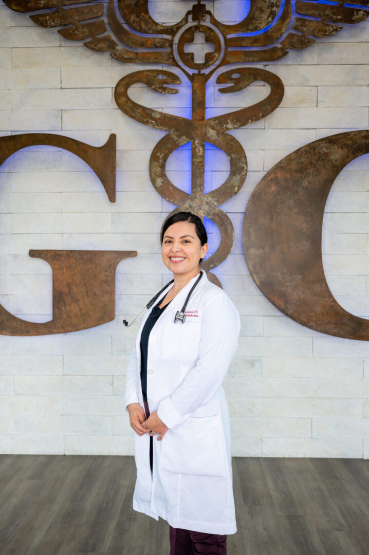 A woman in white lab coat standing next to a large sign.